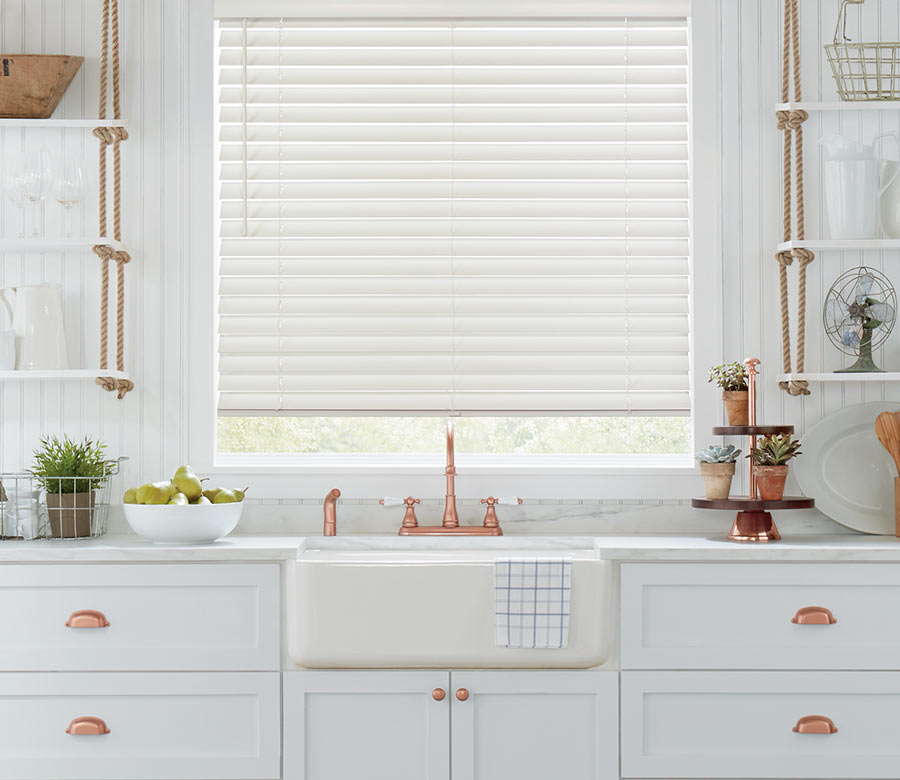 white kitchen with white parkland wood blinds and copper pulls