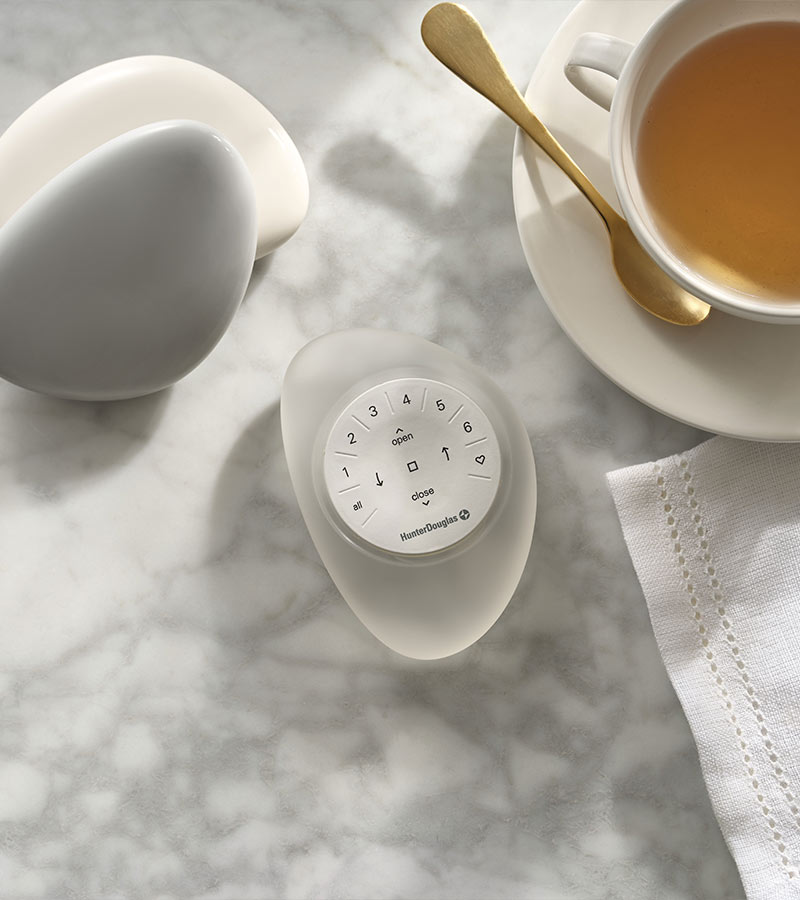 clear pebble remote on marble table next to herbal tea in teacup