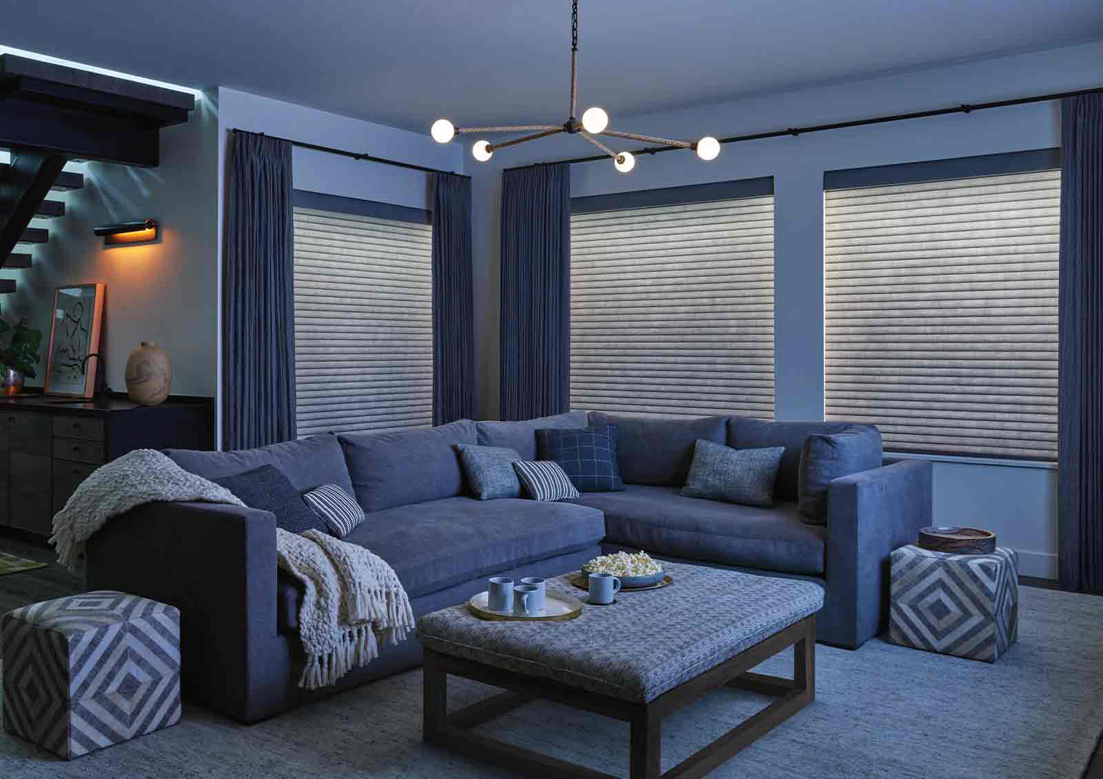 in-home media room with drapery side panels and a light illuminating window shade