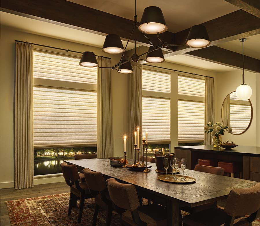 a cozy dining room set for dinner and side draperies layered over aura shades