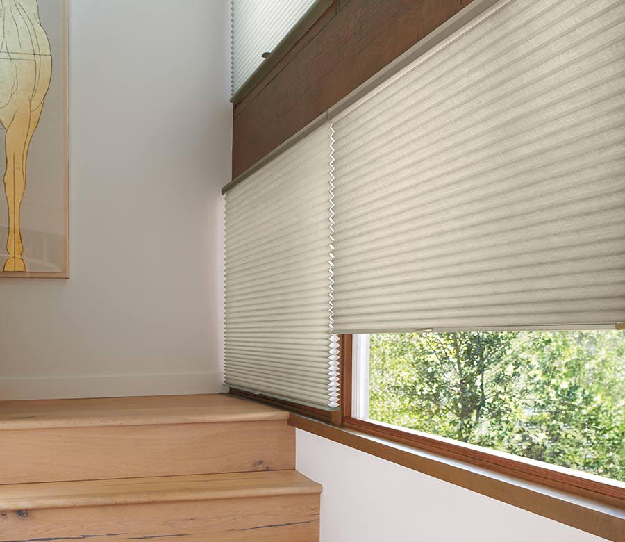 windows over stairwell covered by a beige window shade with honeycomb cells