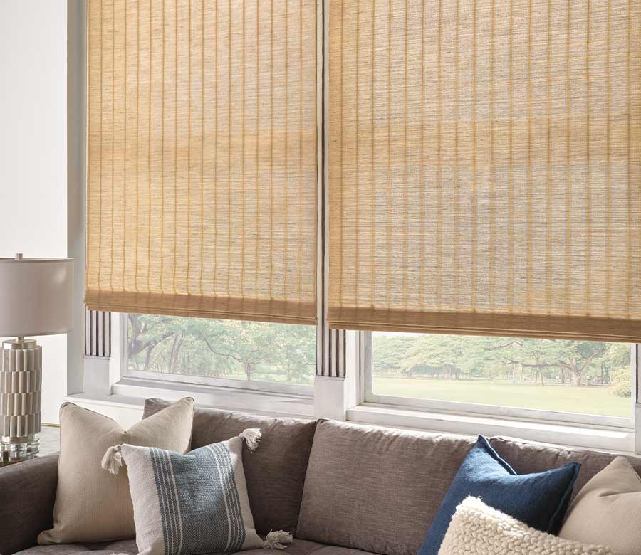 couch with pillows in front of a window with beige woven shades