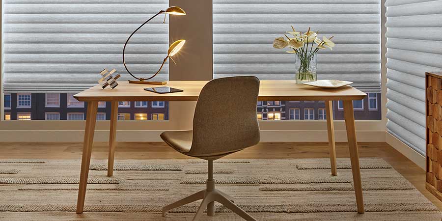 A cozy modern desk with aura illuminated window shades cascaded down the windows floor length windows