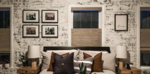 Exposed brick wall has a bed centered on it with provenance woven woods on the big vertical window directly behind the bed