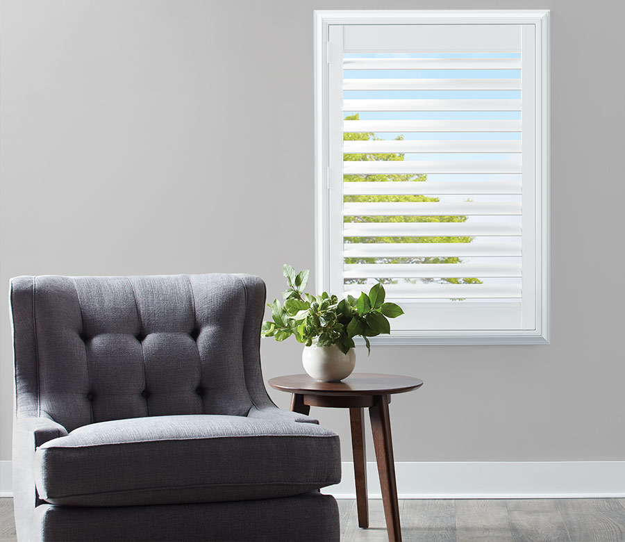 white painted interior shutters on standard window next to gray upholstered chair