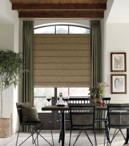 olive green draperies with beige roman shades over window with arched black window trim in Omaha living room