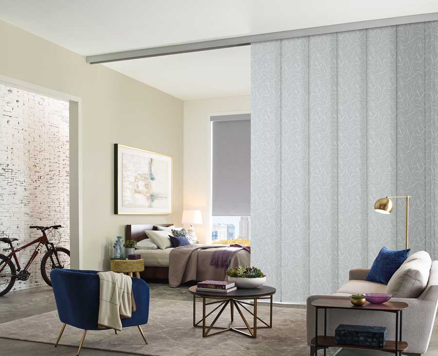 Skyline® Panel Track Blinds that divide a bedroom space from the rest of the living area.