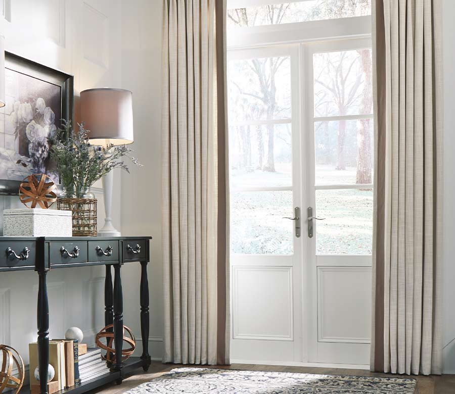 pinch pleat drapes cover french doors with black curtain rod